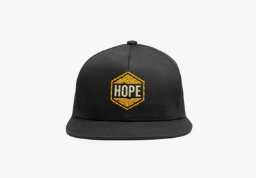 Black flat-bill snapback cap with gold HOPE hexagon embroidery on left panel